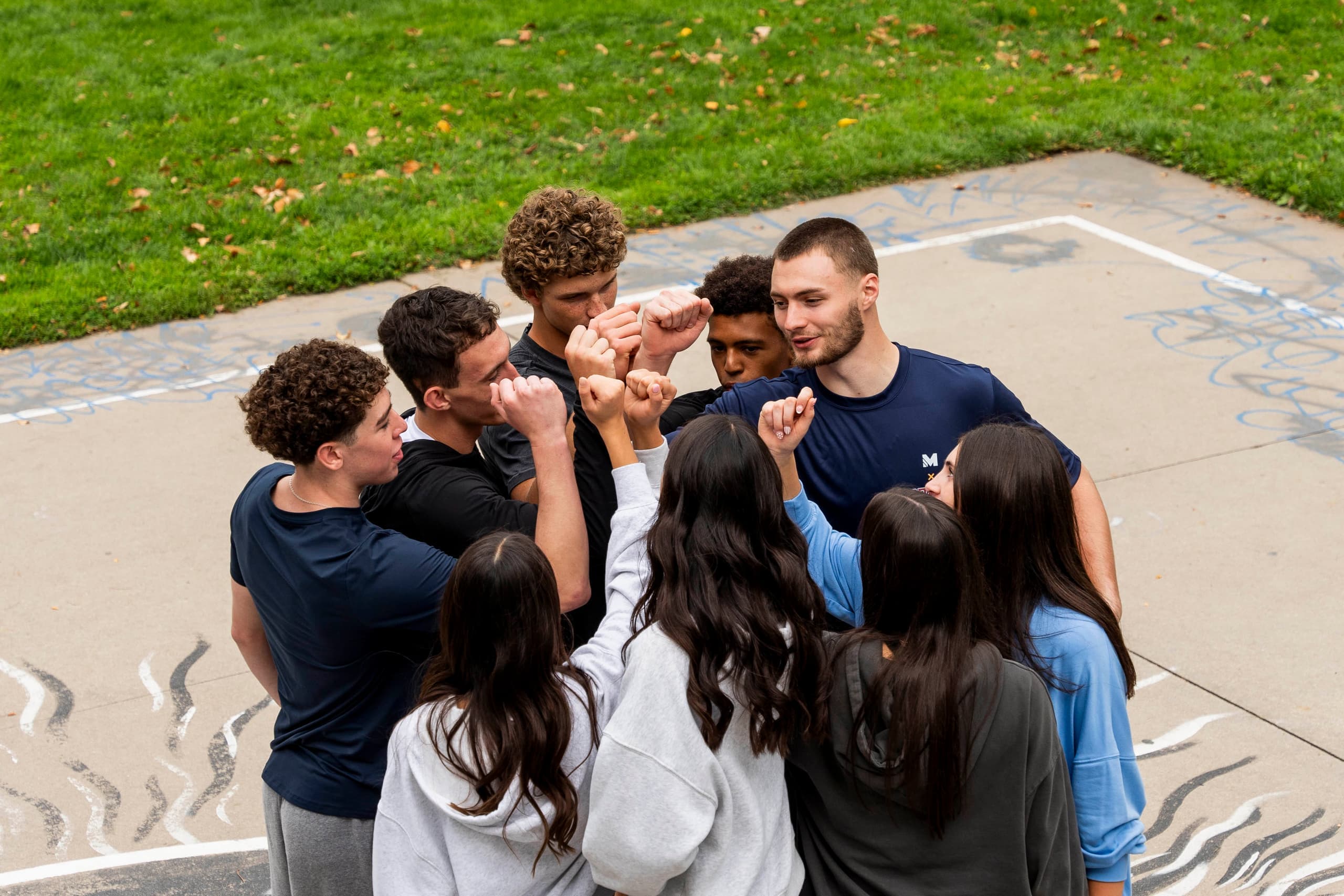 Christian Braun and a group of young people huddling together on an outdoor court.